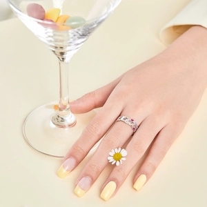Détail d'une bague en argent S925 avec pierres roses sur main devant fleurs