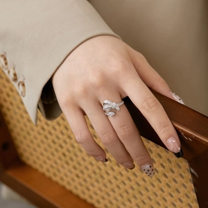 Macro shot of S925 silver bow ring with sparkling zircons worn on hand near wood