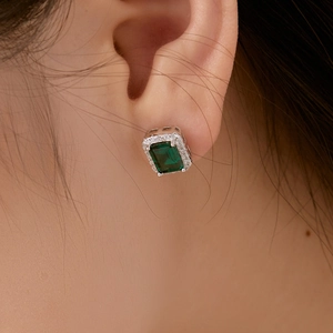 Gros plan d'une boucle d'oreille S925 en émeraude halo avec sertissage de zircons fins