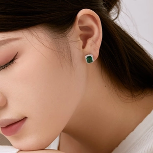 Gros plan de boucles d'oreilles en argent S925 avec zircon vert sur l'oreille