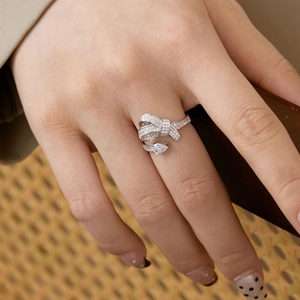 Close-up of S925 silver bow ring with zircon inlay and pear-cut stone on a finger