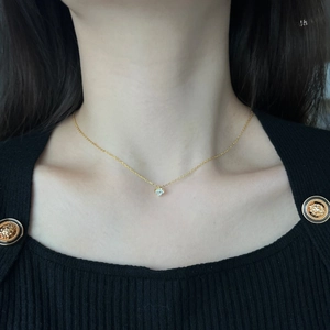 Gros plan d'un collier trèfle à quatre feuilles doré avec cristaux sur un pull noir