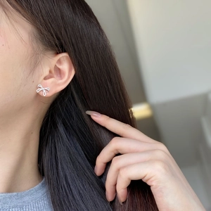 Detail of silver bow earrings with pavé zircons worn by a model for a stylish look
