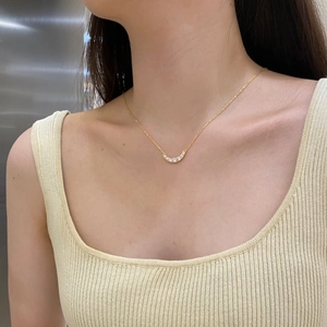 Close-up of elegant gold U-shaped pendant with five sparkling zircons on a model