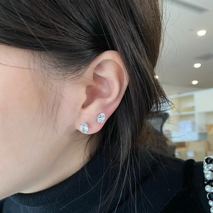 Close-up of elegant oval-cut cubic zirconia stud earrings on ear showing sparkle