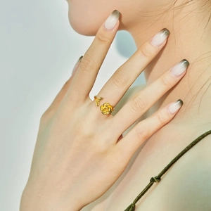Detail eines goldenen Rosenrings mit filigranen Blütenblättern am Finger eines Models