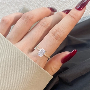 Macro shot of rectangular radiant cut engagement ring with gold band and side diamonds