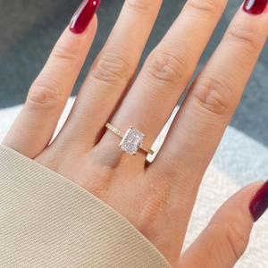 Close-up of a gold ring with a rectangular zircon stone worn on a model's finger
