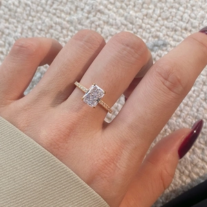 Macro view of radiant cut gemstone engagement ring with pavé diamond band