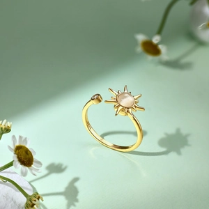 Nahaufnahme des goldenen S925 Silber Sonnenrings mit Opal auf grünem floralem Hintergrund
