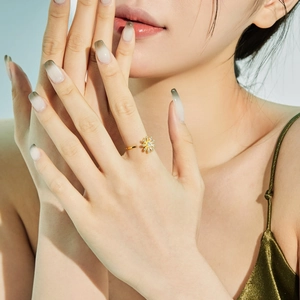Detail eines verstellbaren Gold-Sonnenblumenrings mit Zirkonia an einem Frauenfinger