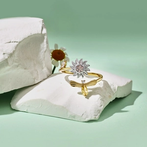 Makroaufnahme von Sonnenblumen- und Bienenring mit rosa und gelben Edelsteinen auf Stein