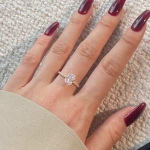 Detail of gold engagement ring with rectangular zircon and diamond accents on model hand
