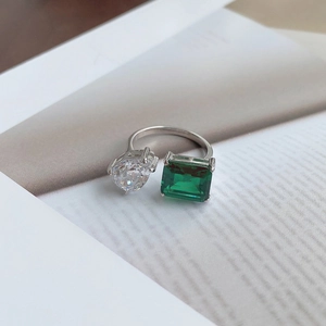 Macro shot of S925 silver ring featuring pear-cut diamond and emerald-cut green stone