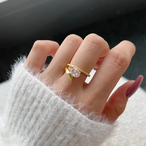 Close-up of elegant gold ring with oval pink stone and pavé diamonds on finger