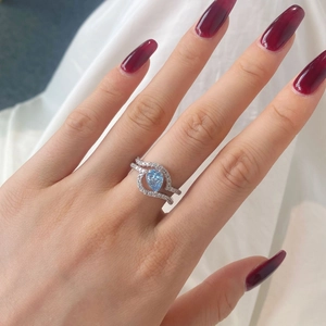 Detalle macro de anillo de circón azul pera con banda cruzada de plata en una mano