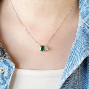 Close-up of S925 silver necklace featuring green emerald and clear heart-cut stones