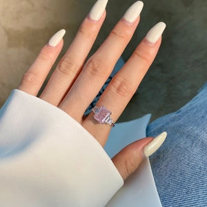 Gros plan d'une bague en zircon rose taille Radiant et pierres taille émeraude sur main