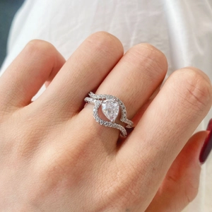 Vista detallada de conjunto de anillos con circonita pera y pavé de diamantes en mano