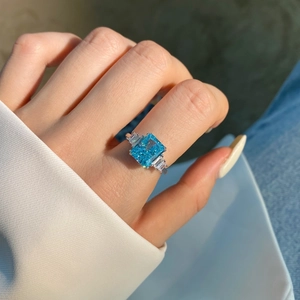 Makroaufnahme eines Ringes mit blauem Edelstein und Baguette-Diamanten an der Hand