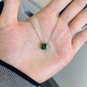 Close-up of S925 silver necklace with emerald-cut green gem and heart-shaped pendant