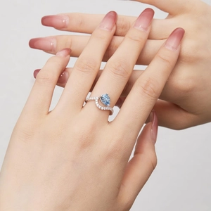 Detalle de anillo de plata S925 con piedra azul claro talla pera y banda de diamantes