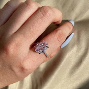 Close-up of pink oval cut zircon ring with silver band on hand in natural light