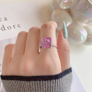 Close-up of radiant cut pink stone ring with micro-pave diamond band worn by model