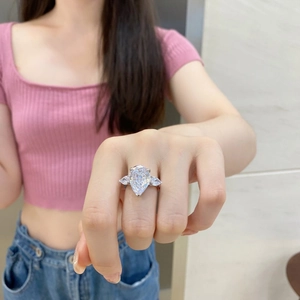 Gros plan sur bague en argent avec une grande pierre rose en forme de poire sur main