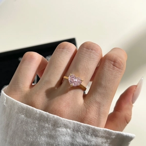 Detailed view of pink heart-shaped crystal ring with gold plating on model's hand
