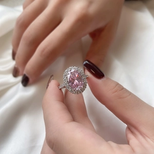 Gros plan d'une bague en argent S925 avec une pierre rose ovale et des diamants halo