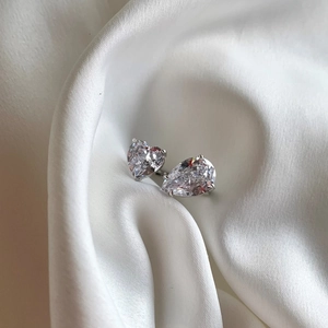 Detalle del anillo de plata S925 con piedras de corte corazón y pera sobre seda blanca