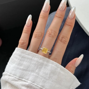 Detail of cushion-cut yellow stone ring with pave diamond band on a finger