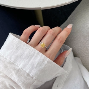 Close-up of square yellow gemstone ring with pavé diamond band on a hand