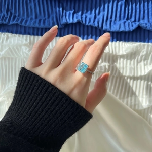 Macro detail of rectangle cut blue zircon ring with micropave diamonds on a hand