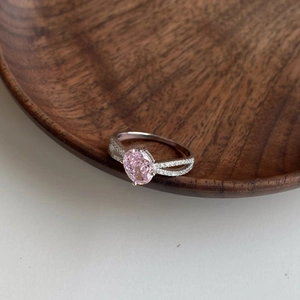 Detailed close-up of oval pink zircon set in silver with split-shank micro-pave diamonds