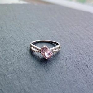 Macro shot of oval pink zircon set in a silver ring with dual-row pave-set diamonds