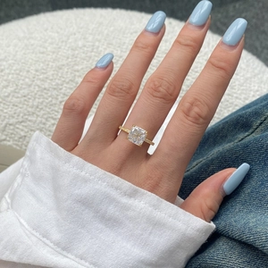 Gros plan d'une bague à diamant carré avec monture micro-pavé dorée sur la main