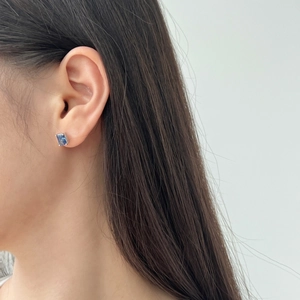 Close-up of S925 sterling silver stud earring with square cut blue gemstone on ear