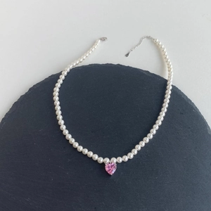 Detail of s925 silver necklace with white pearls and pink heart-shaped zircon pendant