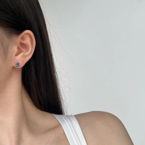 Close-up of sparkling blue square-cut crystal silver stud earring worn by a model