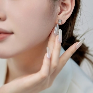 Macro close-up of S925 sterling silver square-cut diamond stud earrings on ear lobe