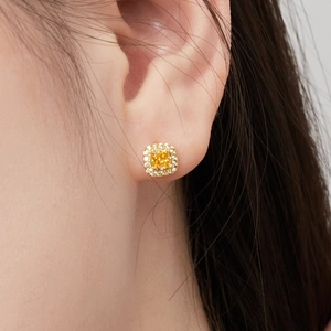 Gros plan d'une boucle d'oreille en zircon jaune taille coussin avec entourage de diamants