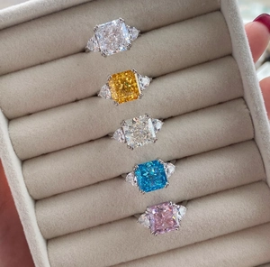 Close-up of five colorful radiant cut high carbon diamond rings in luxury velvet box