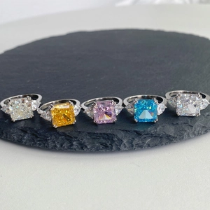 Close-up of five colorful radiant cut carbon diamond rings on black stone plate