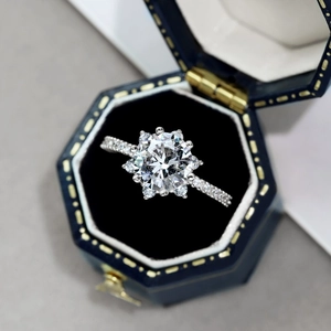 Makroaufnahme von Silberring mit Zirkonia-Blume in einer blauen Samtschachtel