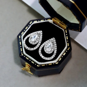 Primer plano de pendientes de plata S925 con diamantes de pera en estuche azul elegante