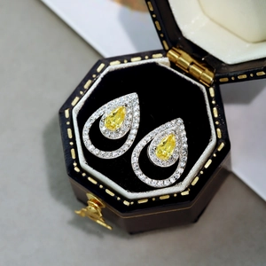 Detalle macro de pendientes de gota amarillos con doble halo en estuche de joyas vintage