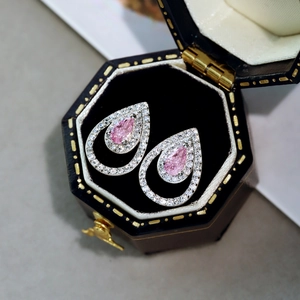 Vista macro detallada de pendientes de zafiro rosa en forma de gota con halo de diamantes