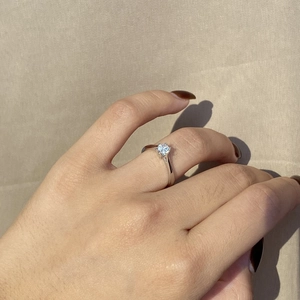 Detailed view of a classic six-prong solitaire ring with a sparkling zircon on a finger